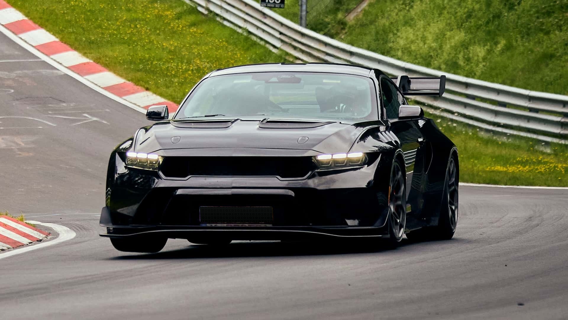 A glossy black Ford Mustang GTD lifting its inside front wheel at the Nürburgring